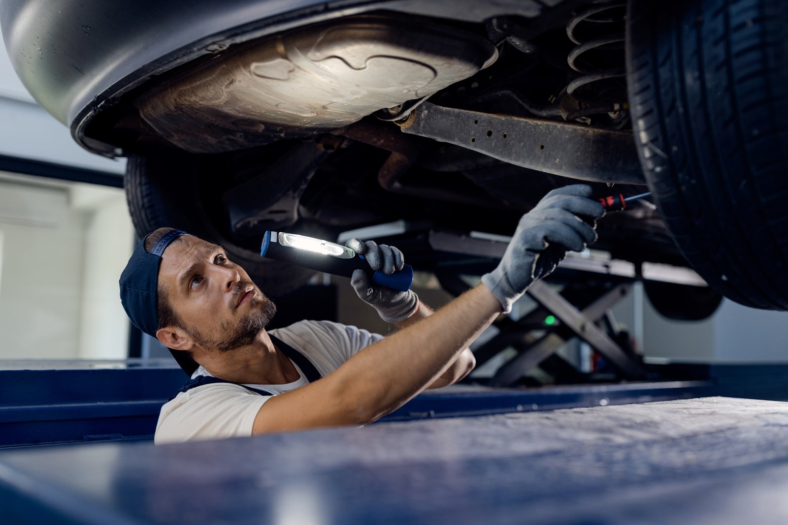 Technician inspecting a car's undercarriage